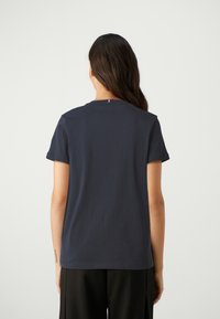 Navy blue short-sleeve T-shirt made of cotton, featuring a crew neck and a small red, white, and blue accent at the back.