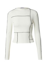 Witte ribgebreide lange mouw top met zwarte contrasterende naden en geometrische stikdetails, met een ronde halslijn en een getailleerde silhout. 
