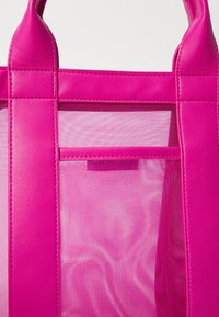 Rosa tote-väska med en kombination av slätt läder och mesh-paneler. Strukturerad design med dubbla handtag och diskreta sömnadsdetaljer.