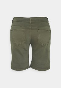Olivově zelené šortky s přiléhavým střihem, zadními kapsami a jemnými stehy. Tkanina vypadá hladce a je lehká.