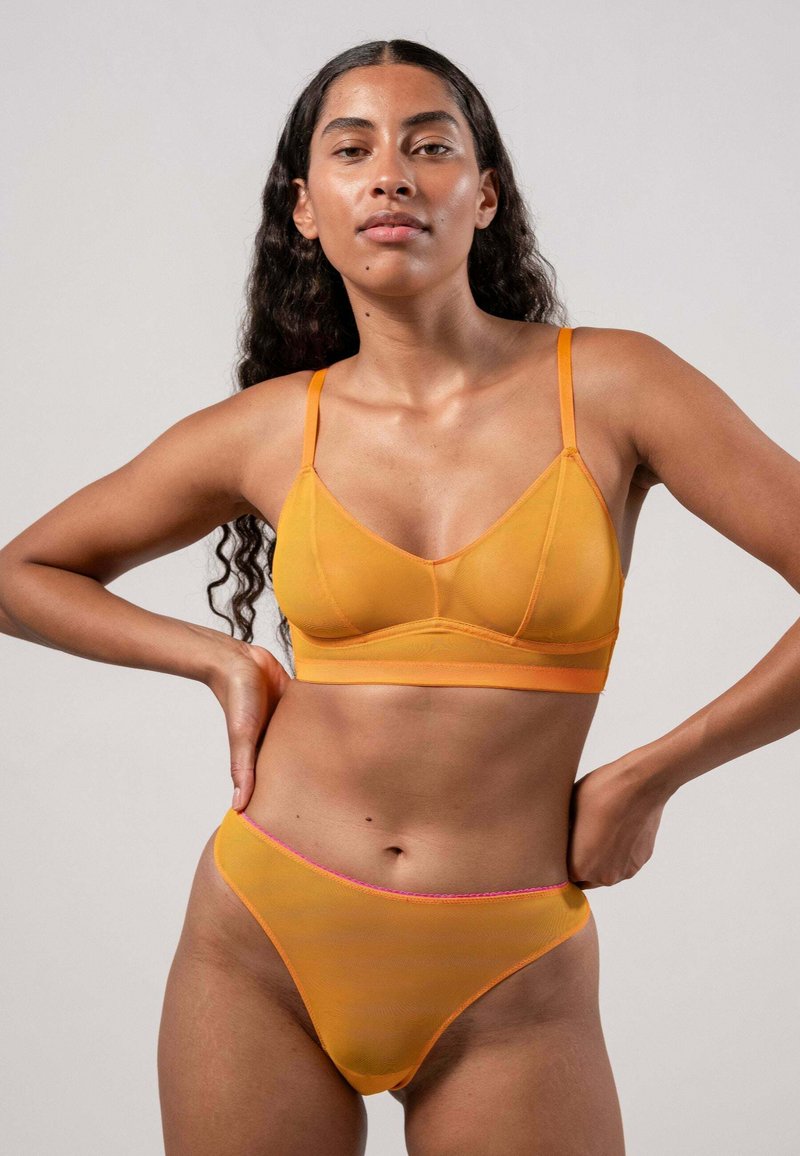 Lichte, doorzichtige oranje bralette met verstelbare bandjes en een bijpassende string met een contrasterende roze tailleband. Glad textuur.