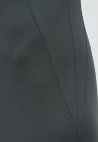 Peça preta ajustada com tecido liso, apresentando detalhes de costura e uma silhueta elegante. Sem padrões ou ferragens visíveis.