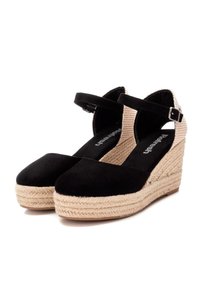Tacones de cuña de ante negro con plataforma de yute trenzado, correa ajustable en el tobillo y paneles laterales de tela texturizada. Diseño de puntera redondeada.
