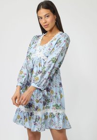 Vestido con estampado floral en tejido azul claro, que presenta mangas largas, un escote con encaje y un dobladillo con volantes decorado con flores multicolores.
