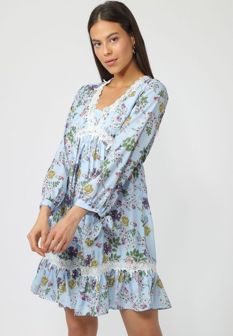 Vestido con estampado floral en tejido azul claro, que presenta mangas largas, un escote con encaje y un dobladillo con volantes decorado con flores multicolores.