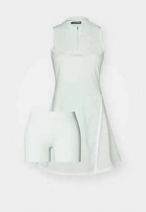 Hele rohelise sportliku kleidi, millel on lukuga kaelus, lühikesed varrukad ja sisseehitatud lühikesed püksid. Kangas näeb välja sile, valgete aktsentdetailidega.