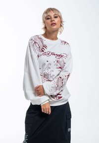 Witte oversized sweatshirt met rode koi-vissen graphics en "Ed Hardy" tekst aan de voorkant. Zachte textuur met ribgebreide manchetten en onderrand.