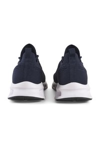 Zapatillas deportivas de color azul marino oscuro con parte superior de punto, entresuela blanca y suela de goma negra. Presenta un tirador en la parte trasera para facilitar el uso.