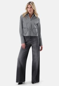 Black and white gingham cropped shirt with long sleeves and heart-shaped patch pockets, paired with wide-leg gray jeans and black heels.