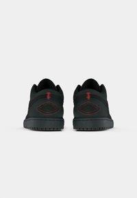 Μαύρα χαμηλά sneakers με υφή στην άνω επιφάνεια, διακοσμημένα με κόκκινα ραφή και περίπλοκο κεντημένο σχέδιο στη φτέρνα. Ελαστική σόλα για καλύτερη πρόσφυση.