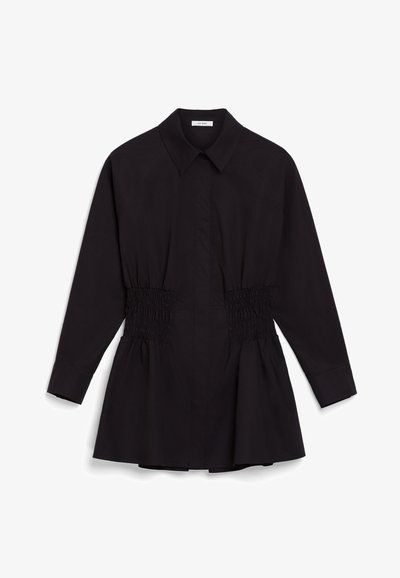 Maglietta nera a maniche lunghe con colletto a punta, caratterizzata da lati arricciati per una vita svasata e un orlo ampio. Tessuto dalla consistenza liscia.