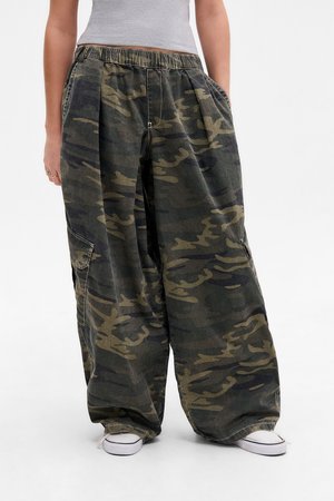 Camo print wide-leg pants in dark green and brown, featuring an elastic waistband and side pockets, made of a textured cotton fabric.