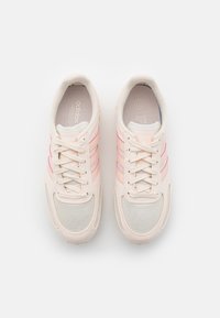 Light beige sneakers with pink stripes, mesh detailing, and textured materials. Round toe, lace-up front, and padded collar.