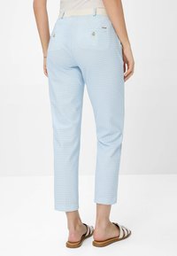 Lysblå ternede bukser med slim fit, der har en talje med en cremefarvet bånd og to baglommer med guldknapper.