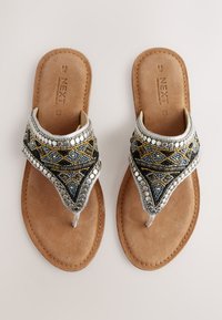 Sandales perlées avec un design à bride intercalaire, ornées d'accents argentés, bleus et dorés, sur une semelle en daim marron avec un bord cousu.