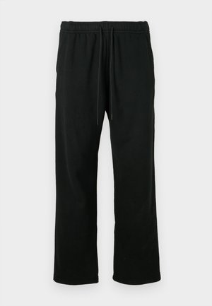 Pantalones deportivos negros hechos de tejido suave, con cintura ajustable, corte holgado y diseño de pierna recta. Sin bolsillos ni patrones.