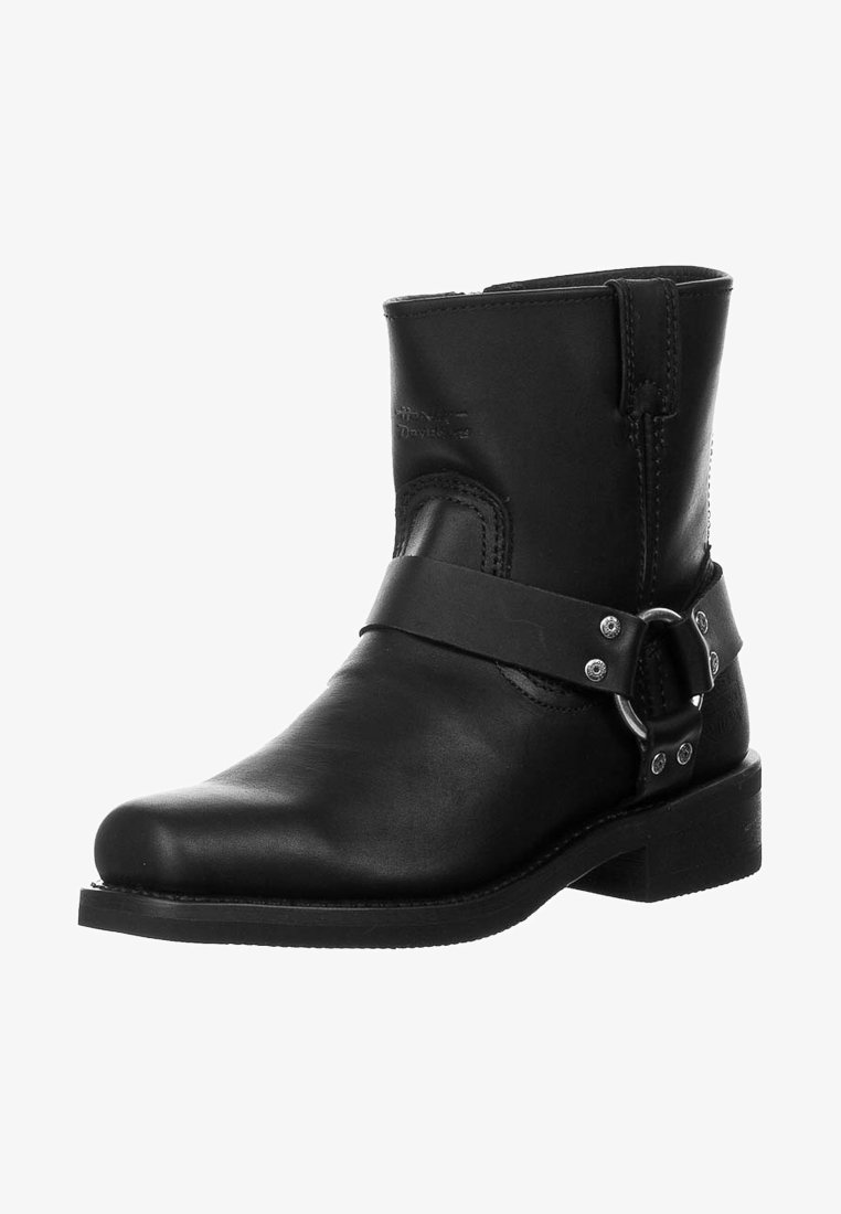 Bottine en cuir noir avec un bout rond, détail de sangle et de boucle, talon bas empilé et texture lisse. Présente des coutures minimales.