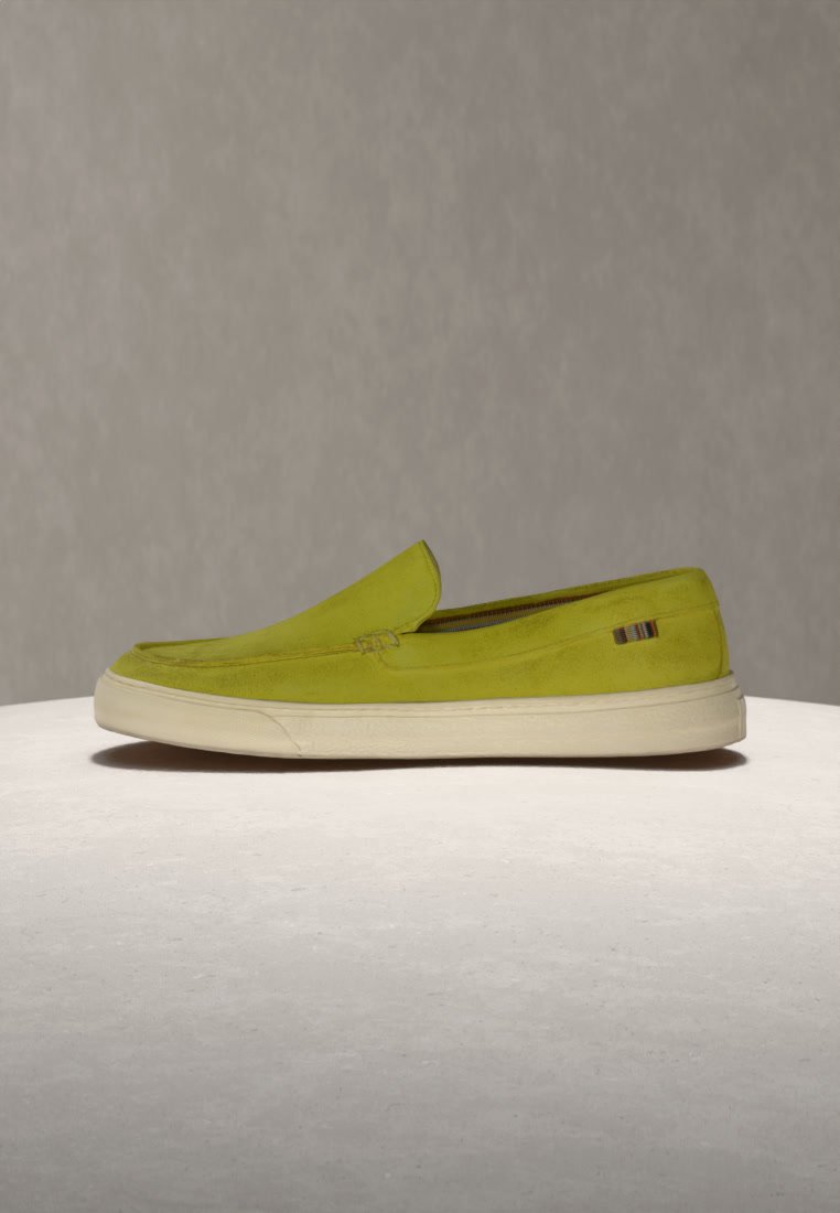 Chaussure à enfiler vert citron vert avec semelle en caoutchouc blanche et petit détail en tissu rayé sur fond neutre.