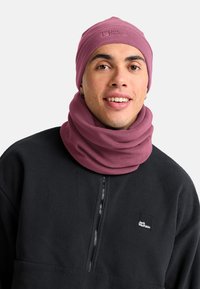 Berretto bordeaux e scaldacollo realizzati in morbido pile testurizzato; indossati con un pullover in pile nero dotato di zip anteriore e patch con logo.