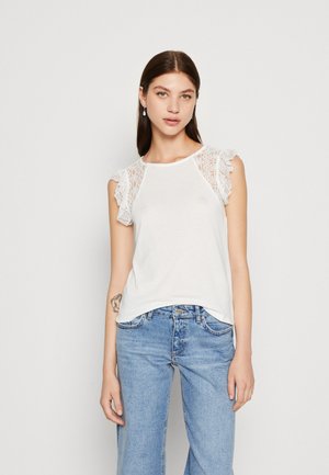 Débardeur blanc avec des manches en dentelle à volants, présentant un col rond et une coupe décontractée, associé à un jean large bleu clair.