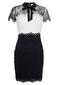 Blonde kjole med sort og hvidt design. Har korte sorte blondesleeves, en høj hals med en sløjfe og en tætsiddende sort blondeskørt.