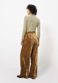 Gestreepte lange mouwen top in groen en beige, gecombineerd met wijde, bruine, fluwelen broeken met een gestructureerde afwerking en achterzakken.