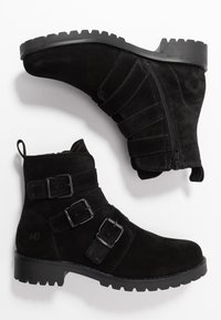 Botas de tobillo de ante negro con punta redondeada, cremalleras laterales dobles y tres correas ajustables con hebilla. Suela de goma duradera con tacos para mayor tracción.