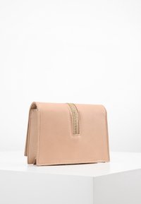 Portfel skórzany w kolorze brzoskwiniowym o ustrukturyzowanym prostokątnym kształcie, z ozdobnym złotym zamkiem błyskawicznym i gładką teksturą.