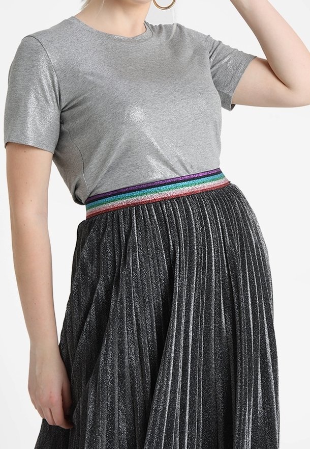 Gray short-sleeve top with a smooth texture, paired with a pleated black skirt featuring a multicolored glittery waistband.