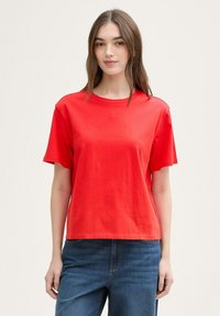 Rode katoenen T-shirt met korte mouwen, een ronde halslijn en een subtiele logodetail. Gecombineerd met blauwe spijkerbroek, casual pasvorm en stijl.