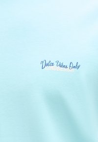 Ανοιχτό μπλε ύφασμα με κεντημένο κείμενο "Dolce Vibes Only" μπλε και "Lindbergh" λευκό από κάτω.