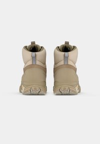 Scarponi da trekking beige con collarino imbottito, tomaia in suede e tessuto, linguette per il tiro e suola in gomma con scanalature profonde per trazione.
