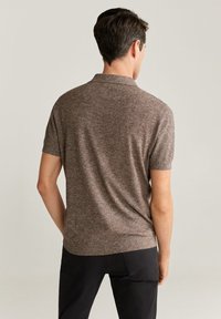 Hnědá polokošile s krátkým rukávem vyrobená z texturované pleteniny, s límcem a žebrovaným lemem, viděná zezadu na neutrálním pozadí.