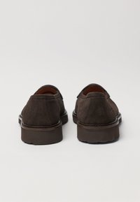 Brown suede shoes with a rounded toe and low heel. The stitching is visible along the edges, and the interior is lined with a lighter material.