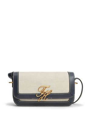 Rektangulær beige stof crossbody-taske med sort læderkant, hvide syninger, guld "TH" logo og justerbar rem på hvid baggrund.