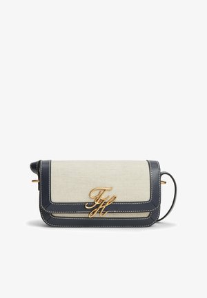 Rektangulær beige stof crossbody-taske med sort læderkant, hvide syninger, guld "TH" logo og justerbar rem på hvid baggrund.