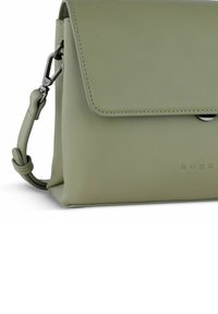 Borsa a tracolla in pelle verde con chiusura a pattina, dotata di un pulsante a scatto in argento e tracolla regolabile. Texture liscia e dettagli di branding minimal.