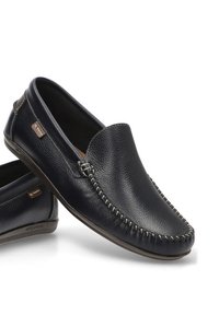 Zapatos de cuero sin cordones en azul marino, con un acabado texturizado, costuras en contraste y un acento de logo marrón. Suela plana de goma para mayor comodidad.