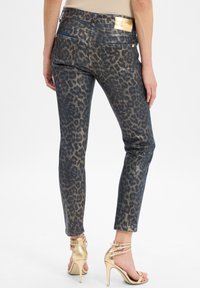 Jeans en denim avec un imprimé léopard et une finition métallisée, présentant une taille mi-haute, des poches arrière et des détails en métal doré.