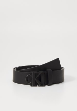 Curea din piele neagră cu o textură netedă, având o cataramă metalică neagră cu logo-ul "CK". Designul este minimal și elegant.