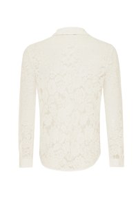 Blusa bianca in pizzo con un motivo floreale, maniche lunghe e colletto. Presenta una texture semitrasparente e un orlo curvo.