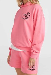 Rosa Kapuzenpullover und passende Shorts, beide aus weichem Material. Mit schwarzem Drucktext: "The Future Surf Society" auf der Vorderseite.