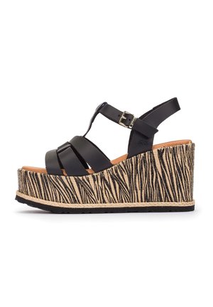 Sandale compensée avec des brides en cuir noir et une boucle à la cheville, comportant une semelle plateforme haute avec un motif zèbre beige et noir.