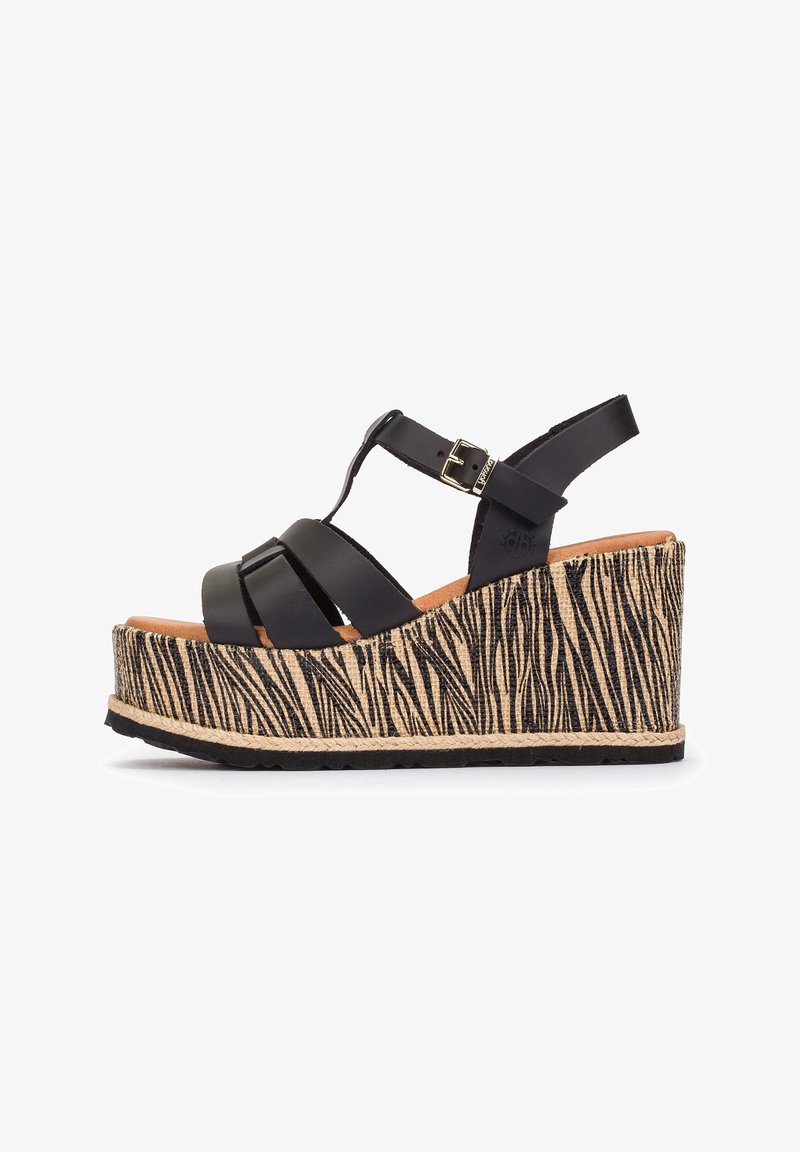 Sandale compensée avec des brides en cuir noir et une boucle à la cheville, comportant une semelle plateforme haute avec un motif zèbre beige et noir.