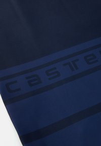 Jūros mėlynos spalvos audinys su lygiu paviršiumi, turintis vidurinę tamsią juostą ir žodį "castre" stora didžiąja raide išilgai juostos.