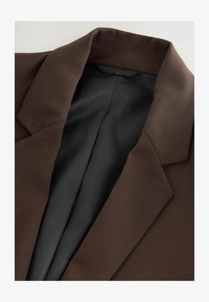Blazer marron avec col cranté, présentant une texture lisse et une doublure en satin noir. Le tissu semble structuré et ajusté.