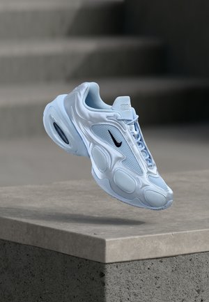 Chaussure de sport bleu clair avec des panneaux en mesh, une silhouette arrondie, des accents texturés et un logo noir. Comprend un amorti à air visible dans la semelle.