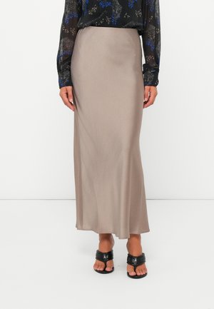 Lang, beige silke skjørt med en jevn tekstur og en lett glans, kombinert med en svart mønstret bluse og svarte sandaler.