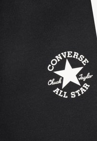 Black textile featuring a white circular logo with a star, text saying "CONVERSE," "Chuck Taylor," and "ALL STAR" in a classic font.