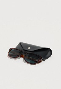 Γυαλιά ηλίου με σκελετό από χελώνα και σκουρόχρωμους φακούς, συνοδευόμενα από μαύρη δερμάτινη θήκη με κλείσιμο με κουμπί. Τετράγωνο σχήμα με υφασμάτινες λεπτομέρειες.